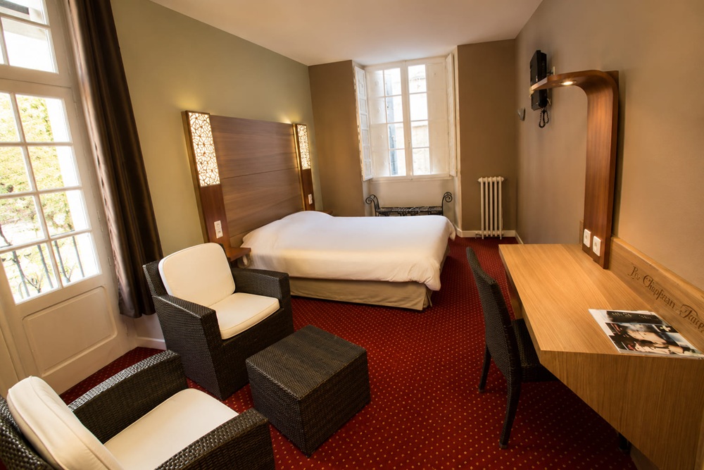 Cameră de oaspeți de hotel cu tăblie din nuc și birou asortat cu bancă integrată pentru bagaje