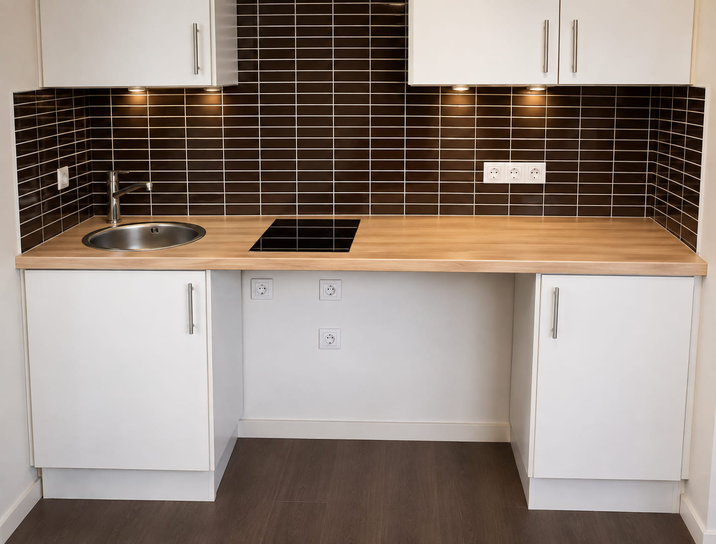 Fitted kitchenette with white handleless fronts and a tiled splashback